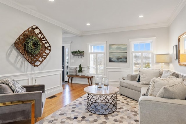 living area featuring light wood finished floors, visible vents, plenty of natural light, and crown molding