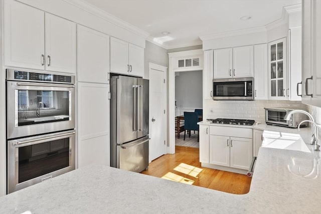 kitchen featuring a sink, tasteful backsplash, appliances with stainless steel finishes, and crown molding