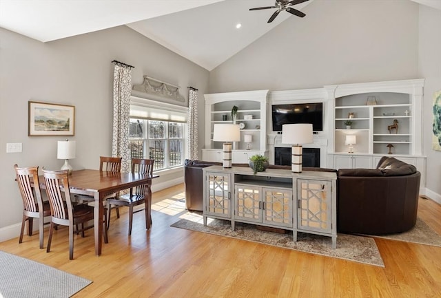 living room with baseboards, high vaulted ceiling, a ceiling fan, and wood finished floors