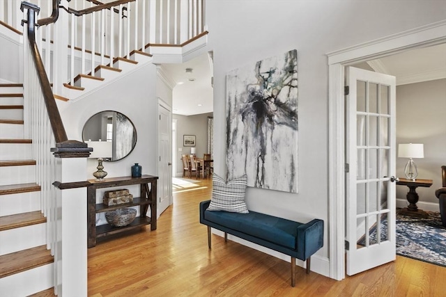 foyer featuring light wood finished floors, stairway, and ornamental molding