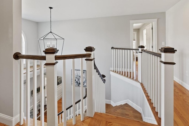 staircase with baseboards, a notable chandelier, and wood finished floors