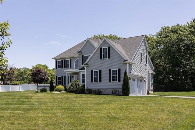 colonial home featuring a front yard, a garage, and fence