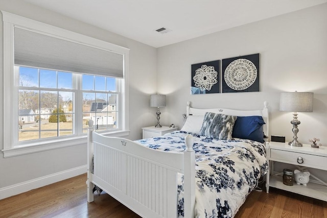 bedroom featuring visible vents, baseboards, and wood finished floors