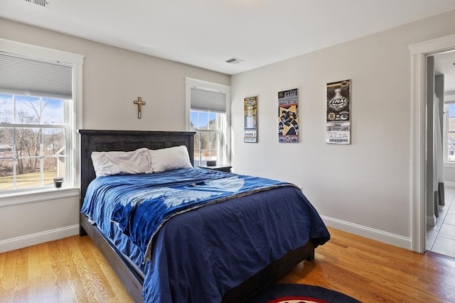 bedroom featuring light wood-style flooring, multiple windows, and visible vents