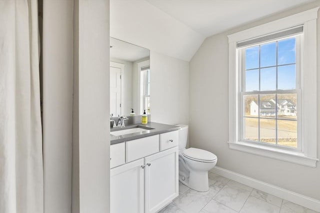 bathroom with baseboards, toilet, lofted ceiling, marble finish floor, and vanity