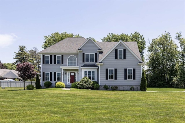 colonial inspired home with a front lawn and fence