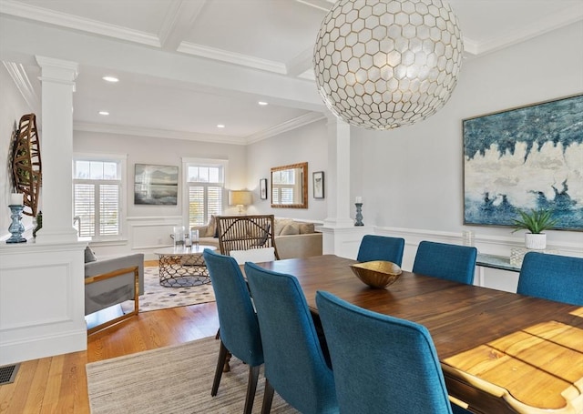 dining area with crown molding, ornate columns, and wood finished floors