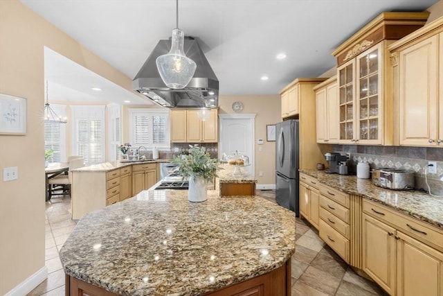 kitchen featuring decorative backsplash, island range hood, a kitchen island, stainless steel refrigerator, and hanging light fixtures