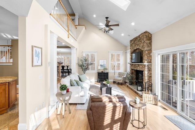 living room featuring a fireplace, light wood-type flooring, high vaulted ceiling, and ceiling fan