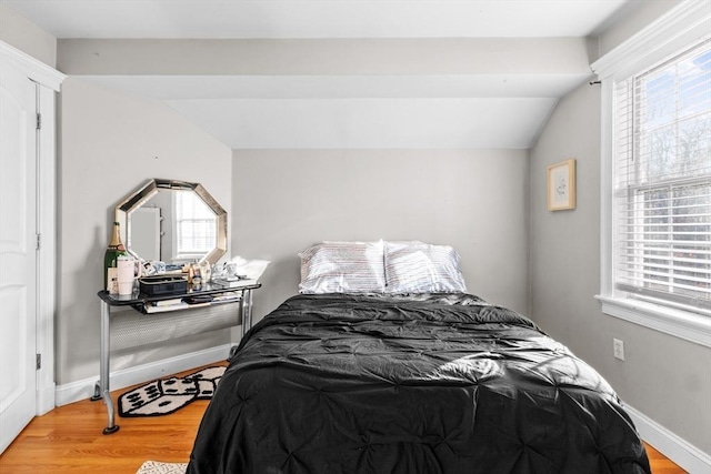 bedroom with wood-type flooring, vaulted ceiling, and multiple windows