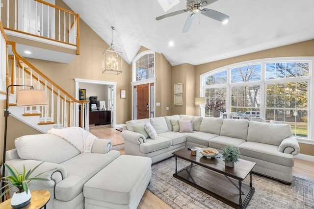 living room with ceiling fan with notable chandelier and light hardwood / wood-style floors