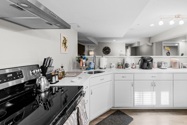 kitchen featuring exhaust hood, white cabinets, sink, light hardwood / wood-style flooring, and electric range