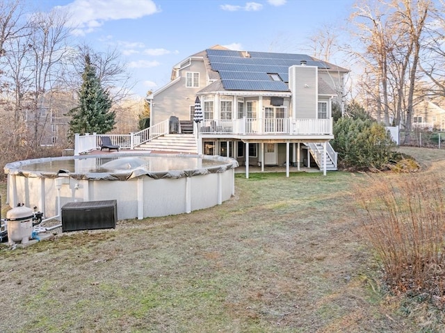 rear view of property with solar panels, a lawn, and a swimming pool side deck