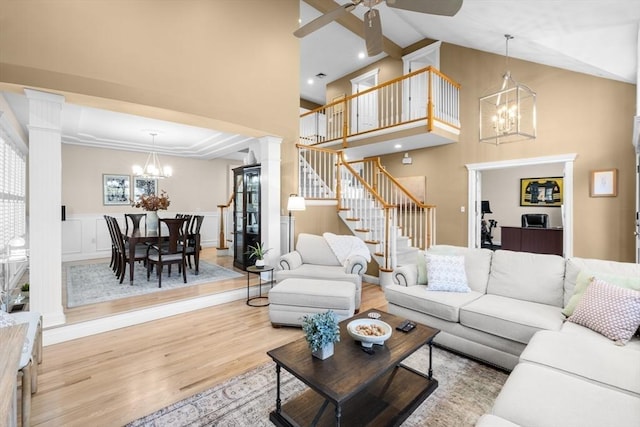 living room featuring ceiling fan with notable chandelier, light hardwood / wood-style floors, ornate columns, and high vaulted ceiling