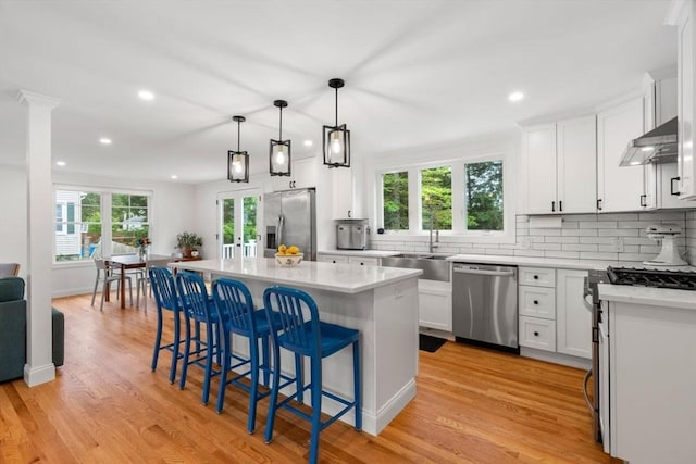 21 Pembrook Rd, North Andover, MA 01845 - kitchen with appliances with stainless steel finishes, extractor fan, backsplash, a kitchen breakfast bar, and light countertops