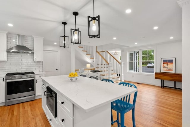 21 Pembrook Rd, North Andover, MA 01845 - kitchen with appliances with stainless steel finishes, wall chimney range hood, backsplash, light wood-style floors, and a center island