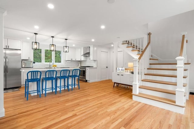21 Pembrook Rd, North Andover, MA 01845 - kitchen with stainless steel appliances, light wood-style floors, white cabinetry, wall chimney range hood, and recessed lighting