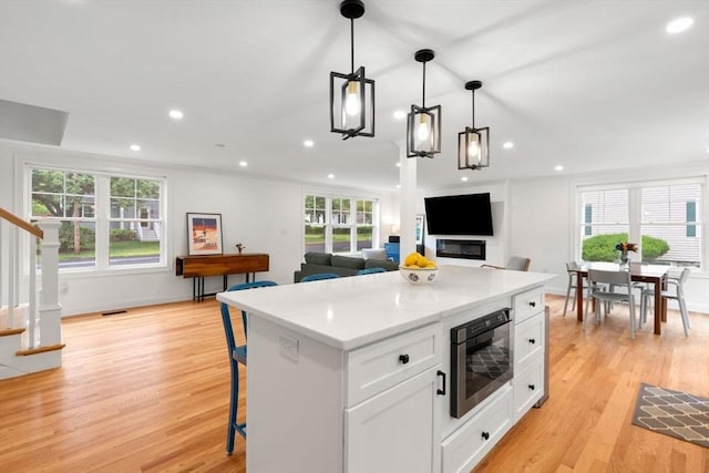 21 Pembrook Rd, North Andover, MA 01845 - kitchen featuring light wood finished floors, white cabinets, recessed lighting, pendant lighting, and a kitchen bar