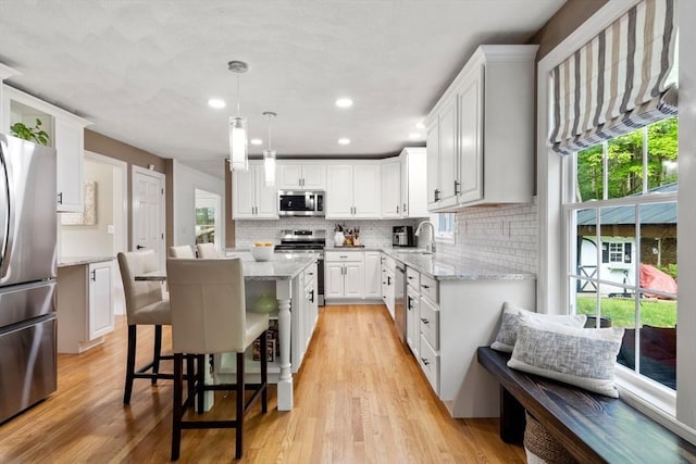 10 Primrose Ln, Westborough, MA 01581 - kitchen with stainless steel appliances, white cabinets, light wood-style flooring, tasteful backsplash, and light stone countertops