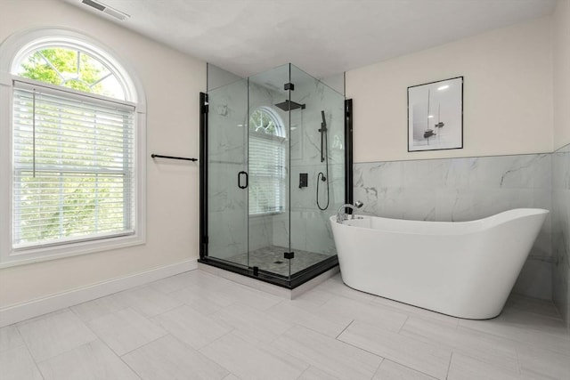 10 Primrose Ln, Westborough, MA 01581 - full bathroom featuring a freestanding bath, a marble finish shower, tile walls, and wainscoting