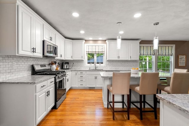 10 Primrose Ln, Westborough, MA 01581 - kitchen with stainless steel appliances, a sink, white cabinets, a breakfast bar, and recessed lighting
