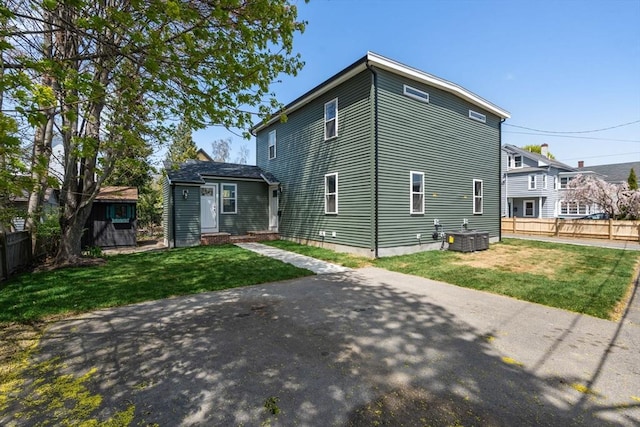 rear view of house featuring fence, central air condition unit, and a yard