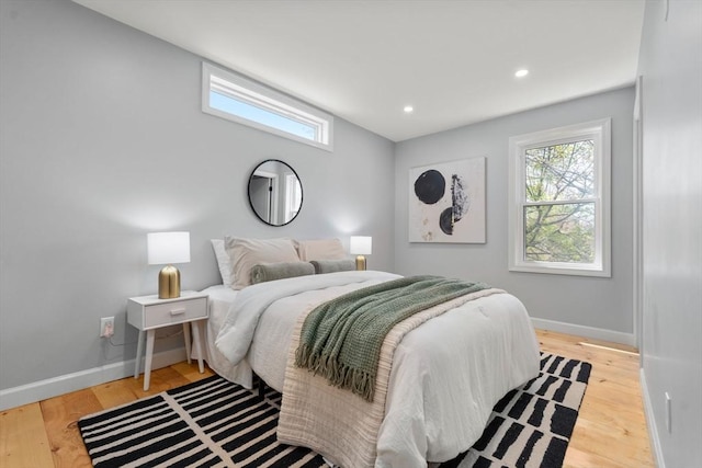 bedroom with baseboards, multiple windows, and wood finished floors