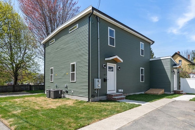 view of front of home with fence, a front lawn, and cooling unit