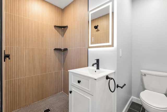 bathroom featuring toilet, tiled shower, tile patterned flooring, and vanity