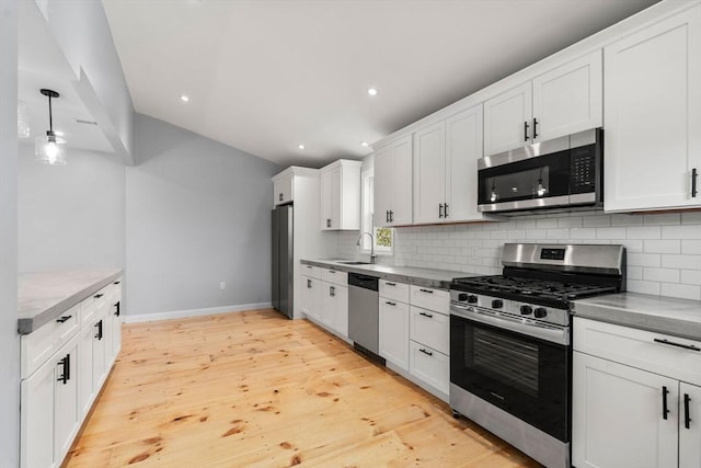kitchen featuring baseboards, white cabinets, tasteful backsplash, a sink, and stainless steel appliances