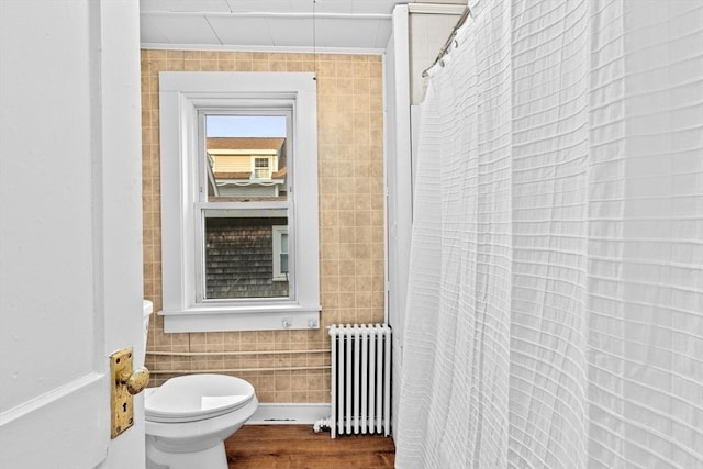 full bath featuring crown molding, toilet, radiator heating unit, wood finished floors, and tile walls