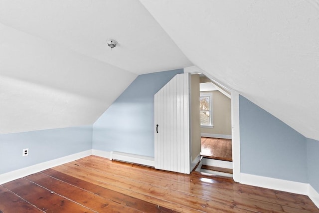 additional living space with a baseboard radiator, baseboards, and hardwood / wood-style flooring