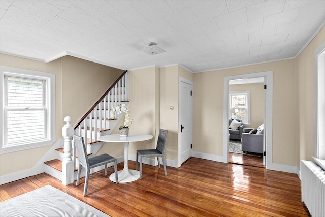 dining space with stairs, radiator, wood-type flooring, and ornamental molding