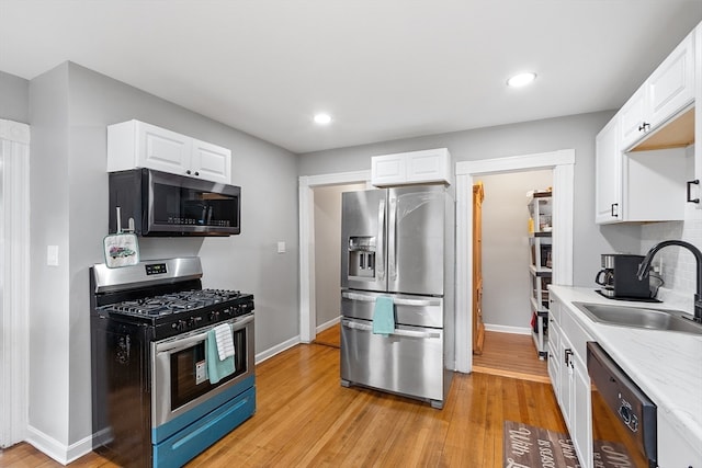 kitchen with white cabinets, stainless steel appliances, light hardwood / wood-style floors, and sink