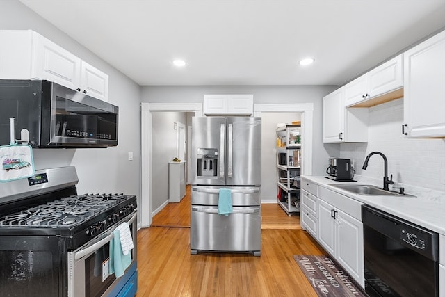 kitchen with stainless steel appliances, white cabinetry, light hardwood / wood-style floors, and sink