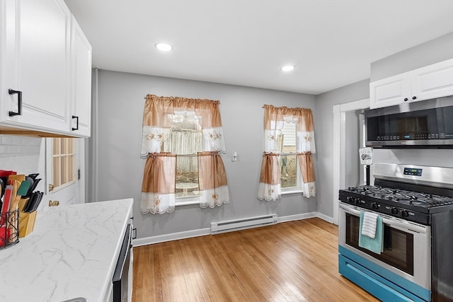 kitchen with white cabinets, light hardwood / wood-style flooring, a baseboard radiator, light stone counters, and stainless steel appliances