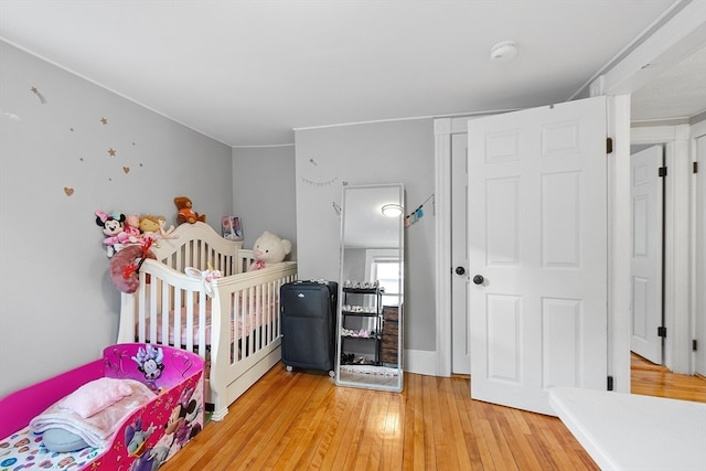 bedroom featuring hardwood / wood-style floors and a nursery area