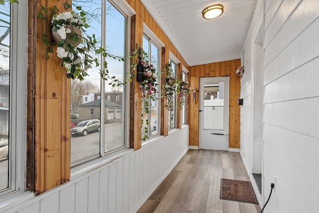 hall featuring hardwood / wood-style floors, wood walls, a wealth of natural light, and vaulted ceiling