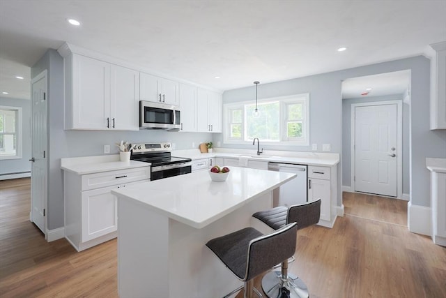 18 Beaumont Rd, Worcester, MA 01604 - kitchen with stainless steel appliances, light wood-type flooring, a kitchen bar, white cabinets, and a baseboard radiator