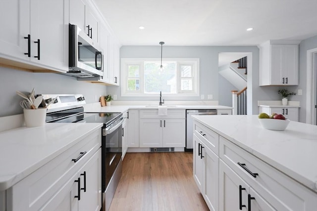 18 Beaumont Rd, Worcester, MA 01604 - kitchen featuring stainless steel appliances, a sink, white cabinetry, wood finished floors, and pendant lighting