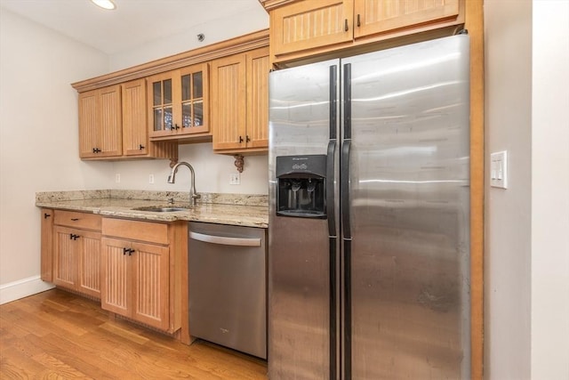 kitchen with sink, light hardwood / wood-style flooring, light stone countertops, and appliances with stainless steel finishes