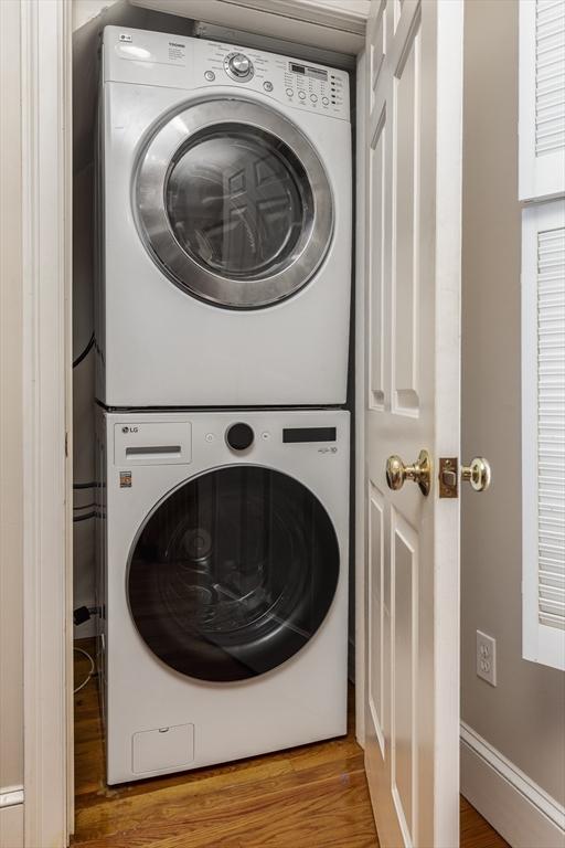 laundry room with wood-type flooring and stacked washing maching and dryer