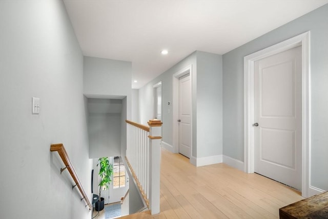 corridor with an upstairs landing, recessed lighting, light wood-style flooring, and baseboards