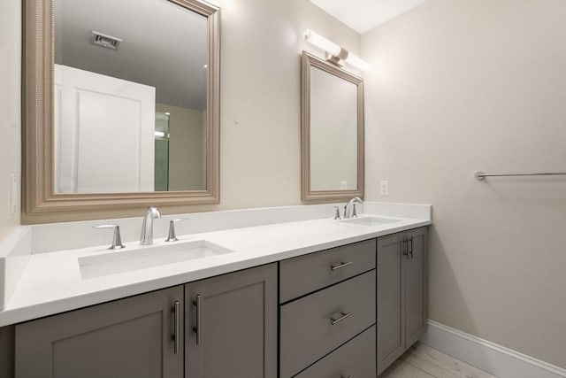 bathroom with a sink, visible vents, baseboards, and double vanity