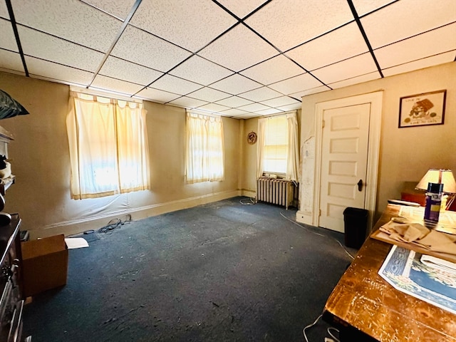 misc room with a drop ceiling, dark carpet, and radiator heating unit