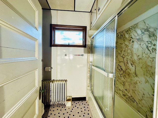 bathroom with radiator heating unit, tile patterned floors, and shower / bath combination with glass door