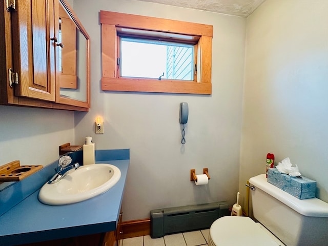 bathroom with baseboard heating, tile patterned flooring, vanity, a textured ceiling, and toilet