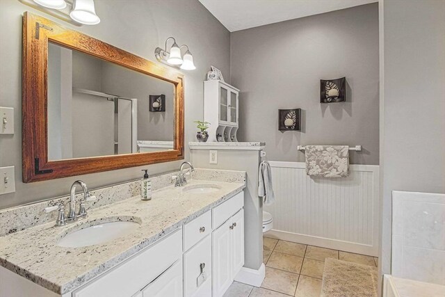 27 Southwick Rd, Sutton, MA 01590 - bathroom featuring toilet, double vanity, a wainscoted wall, a shower with shower door, and tile patterned flooring