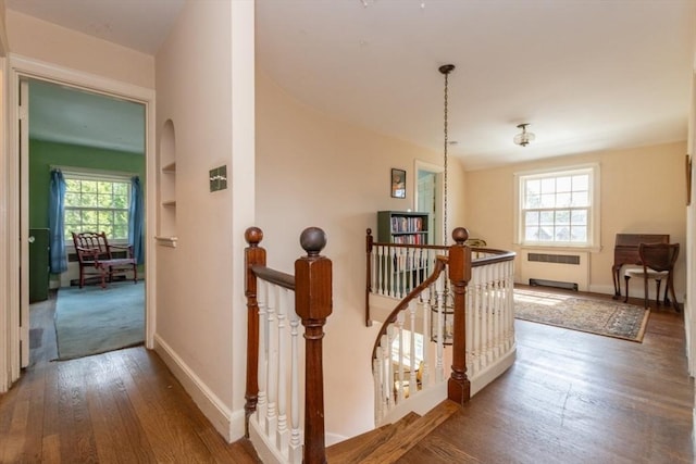 hallway featuring baseboards, radiator, an upstairs landing, and hardwood / wood-style flooring