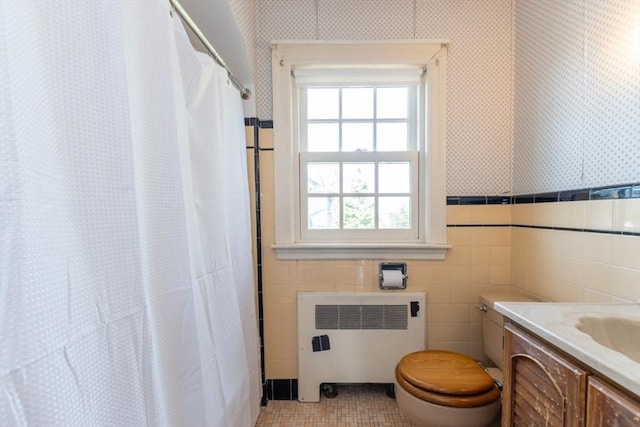 full bathroom with vanity, toilet, tile walls, radiator heating unit, and wallpapered walls